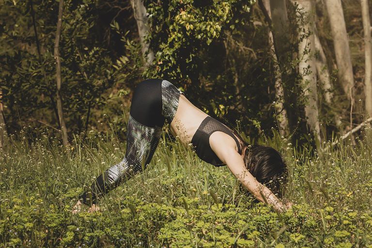 Mujer en un retiro de yoga en la naturaleza practicando la postura de la montaña.