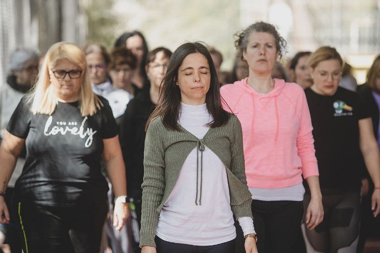 Mujeres caminando con los ojos cerrados en una meditación durante el taller de hipopresivos para mujeres sordas